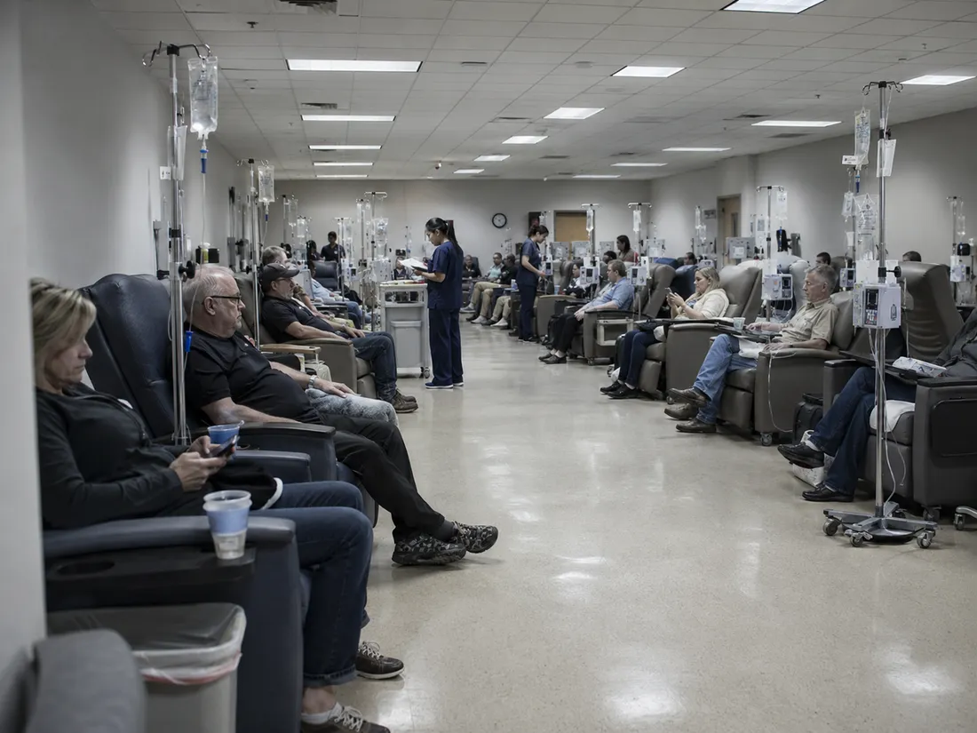 A crowded group treatment room with rows of patients receiving IVs side by side