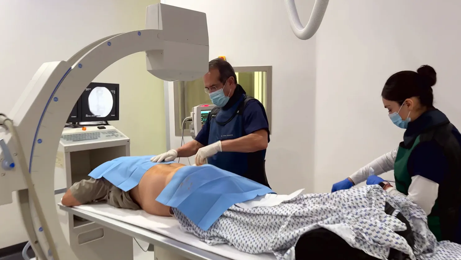 Ken on the table under the X-ray arm as the physician prepares his lower back