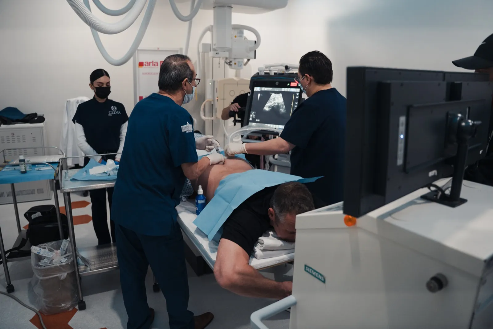 Image-guided procedure underway in the Celva procedure room with ultrasound and a Siemens C-arm